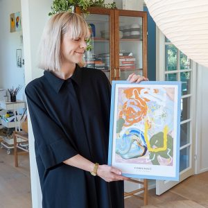 Ida Holm viser den farverige plakat frem